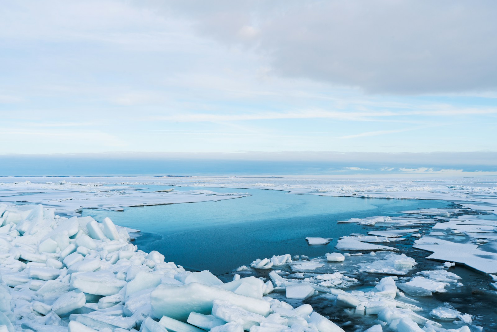 Broken sea ice with a channel of open blue water reaching toward the horizon.